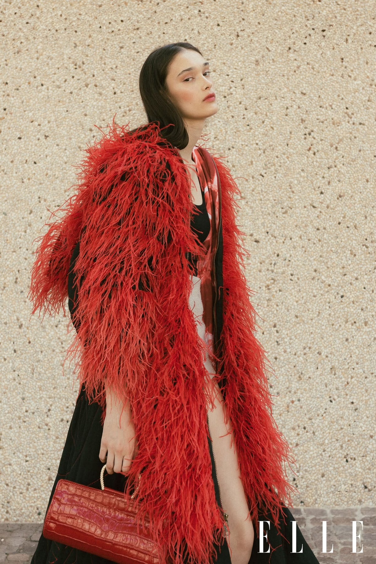 Madison Maison Red Leather Moc Croc Clutch with gold snake handle, carried with a red ostrich feather coat in an ELLE editorial