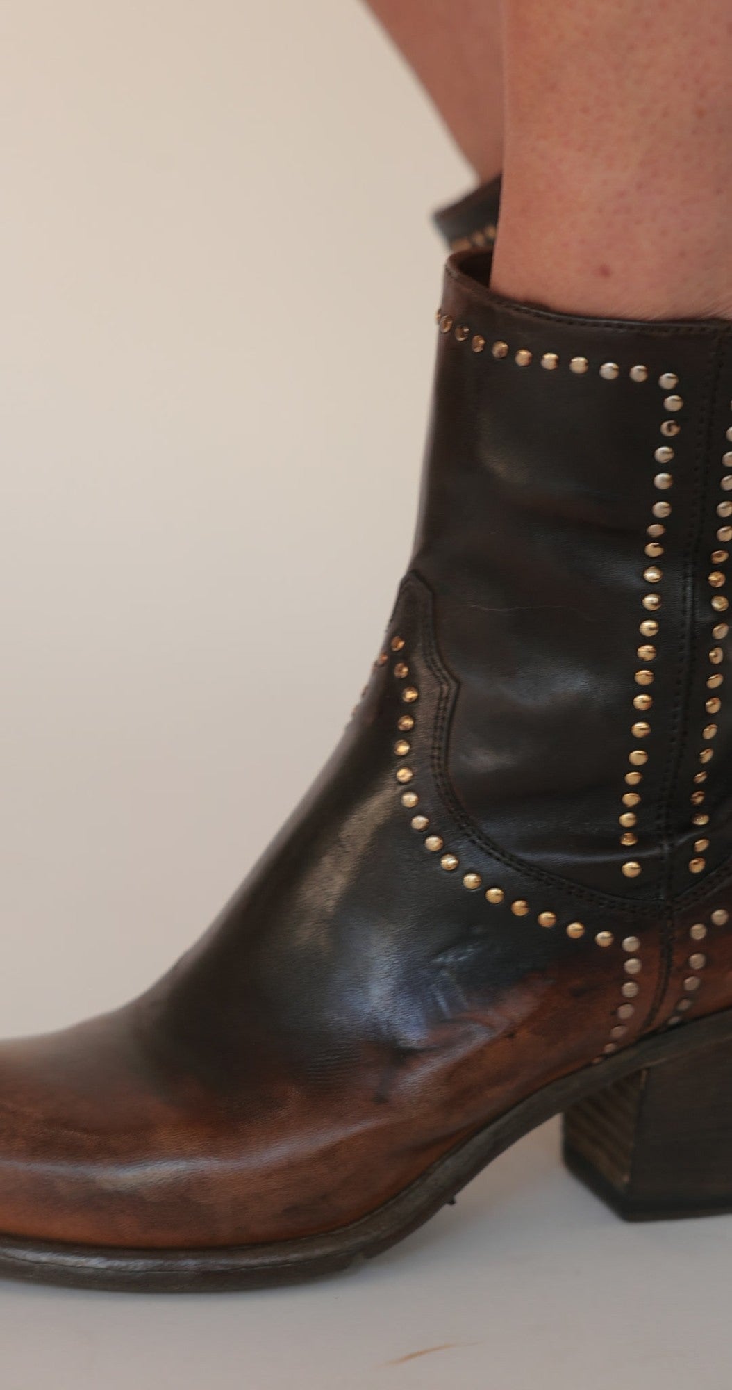 Madison Maison brown leather studded western ankle boots worn on the leg, stud trim along the seams, block heel