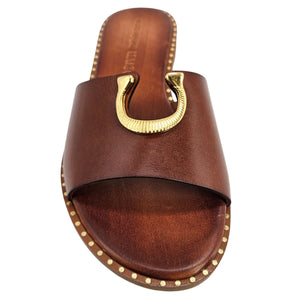 Caramel leather slide sandal close-up with gold horseshoe buckle and stud trim