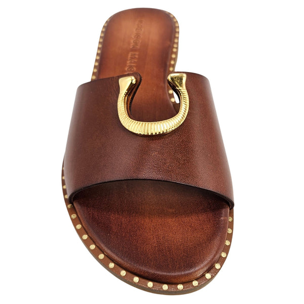 Caramel leather slide sandal close-up with gold horseshoe buckle and stud trim