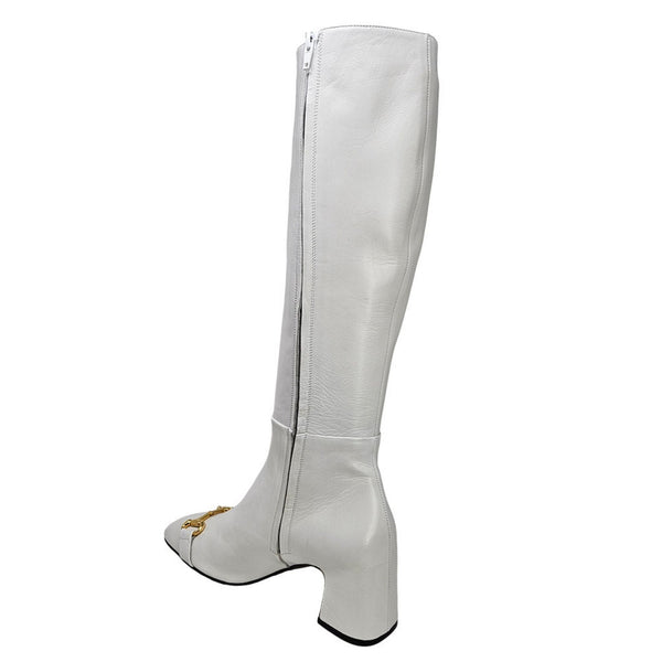 White tall boot with side zipper and gold decorative hardware on shaft