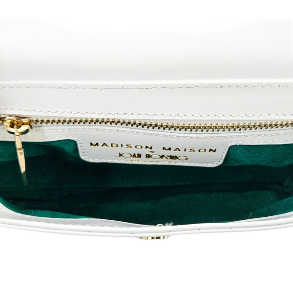 Small crossbody bag interior with green lining, gold zipper, and brand label tag