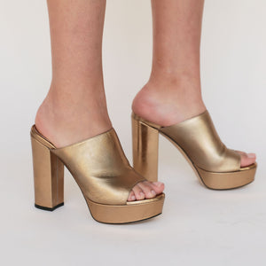 Gold open-toe platform sandals on feet, showing wide block heels and platforms