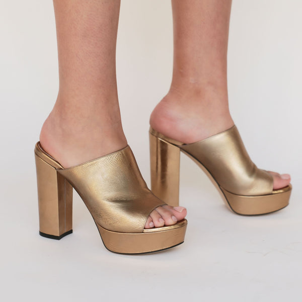 Gold open-toe platform sandals on feet, showing wide block heels and platforms