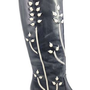 Close view of dark blue leather boot shaft with white floral embroidery accents