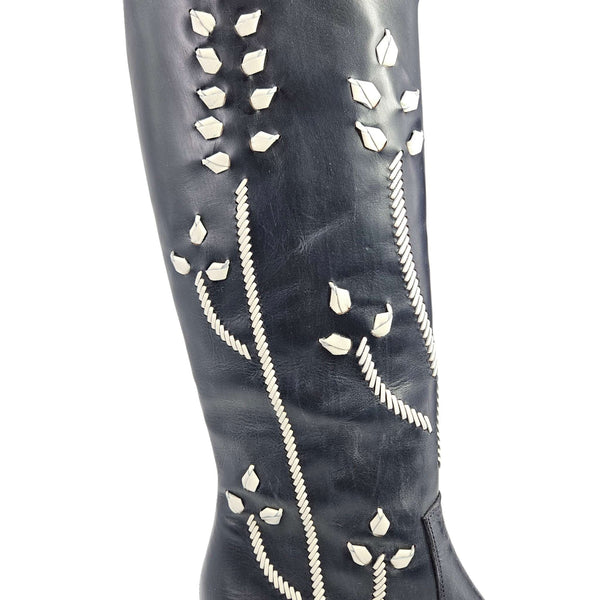 Close view of dark blue leather boot shaft with white floral embroidery accents