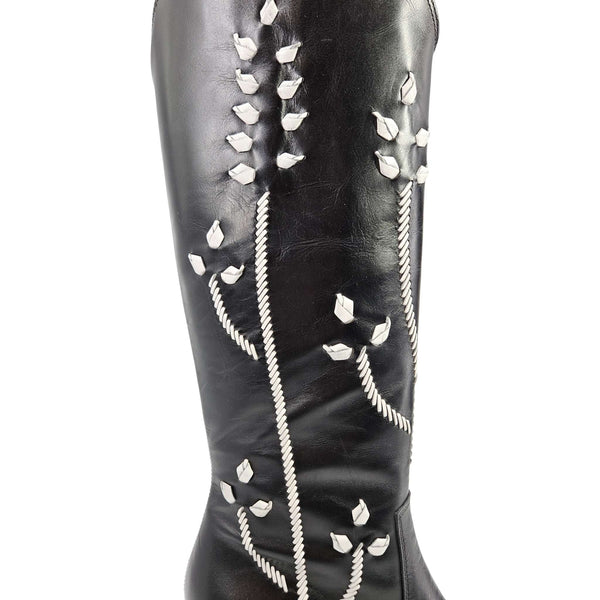 Black tall leather cowboy boot shaft with white floral embroidery close-up detail