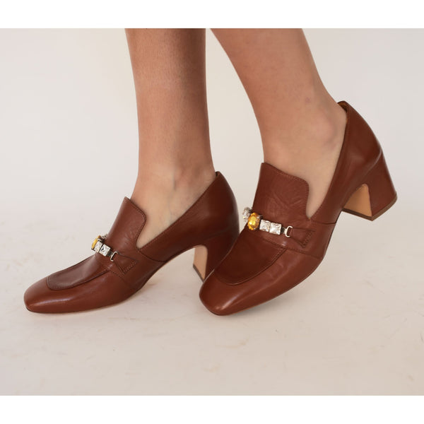 Brown leather mid-heel loafer worn by model; jewel buckle detail on vamp