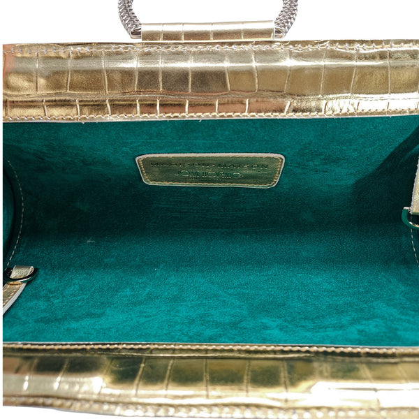 Gold leather clutch open to show teal fabric lining and center label