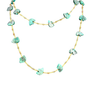 Green stone bead necklace viewed from above with gold-toned chain and drops.