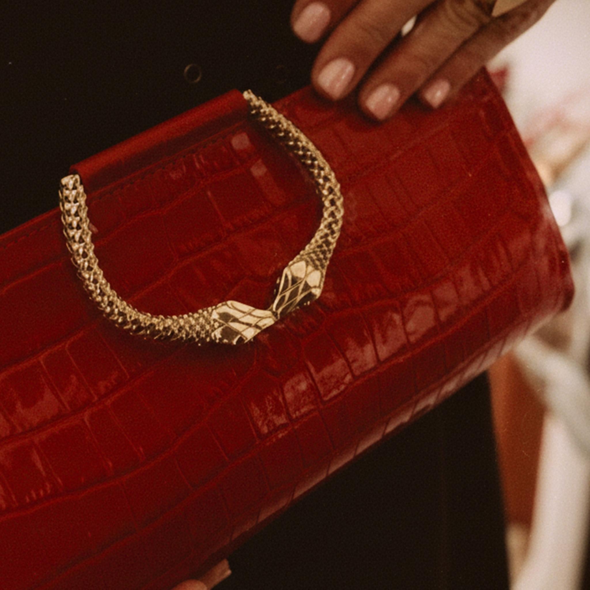 Red clutch with gold handle held by a hand