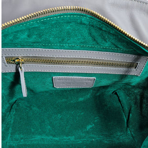 Green fabric lining inside leather tote with gold zipper and logo patch