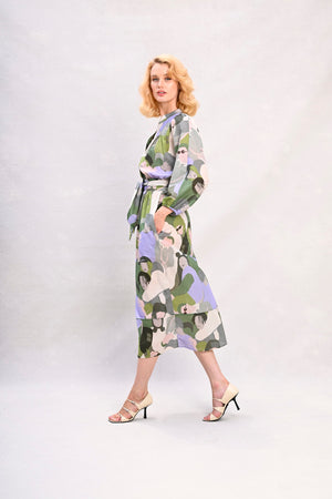 Long shirt dress with waist tie, green and lavender face print, standing full-body