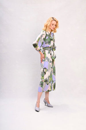 Long shirt dress with waist tie, green and lavender face print, angled front view