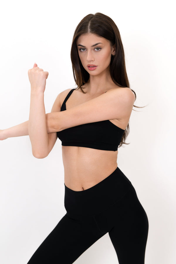 Black sports bra with thin straps and smooth fabric, angled side view