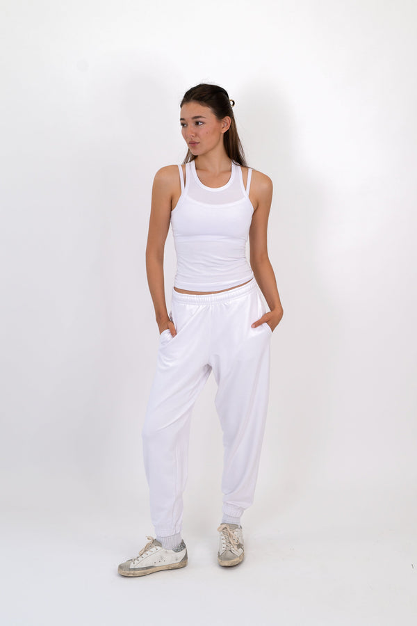 White scoop-neck tank with ruched waist and racerback straps, worn with pants