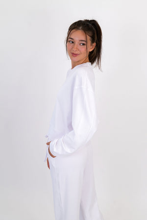 White crew neck pullover, side view, long sleeves and drawstring waist hem.