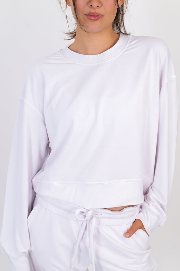 White crew neck pullover with long sleeves and tied drawstring waist hem.