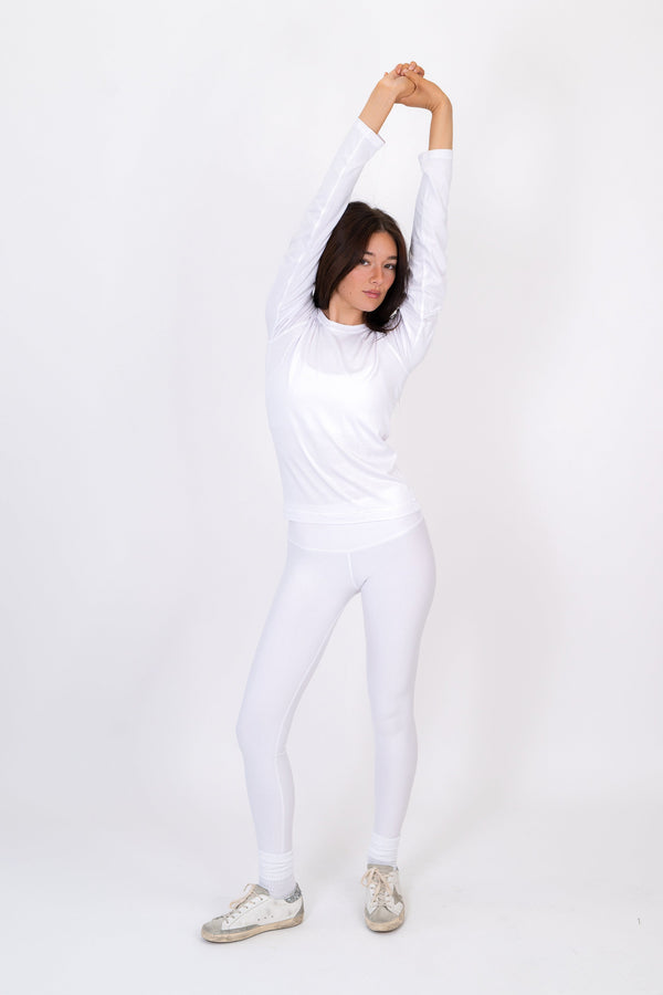 White long-sleeve fitted crewneck shirt, side view with smooth knit and gathered waist seam.