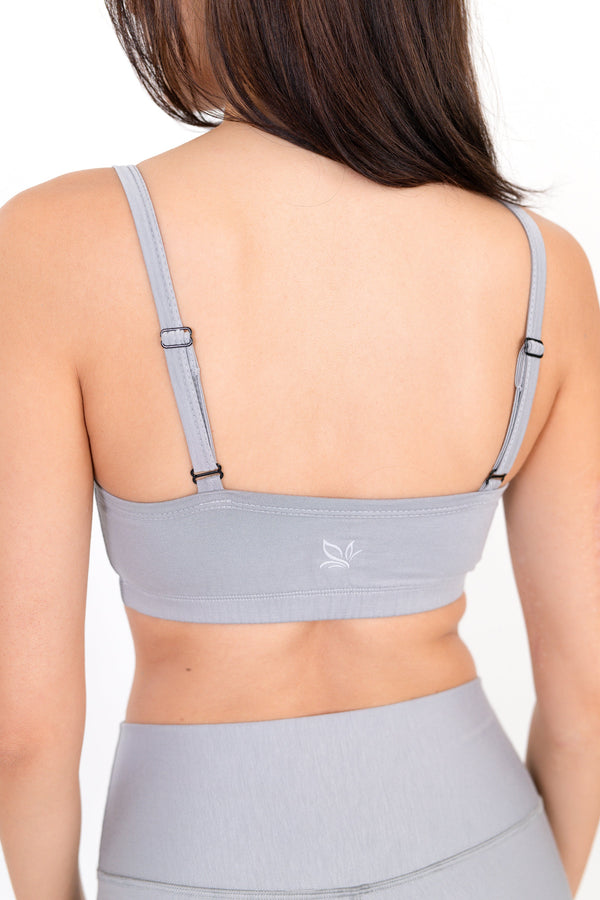 Gray sports bra back view with thin straps and small logo at center