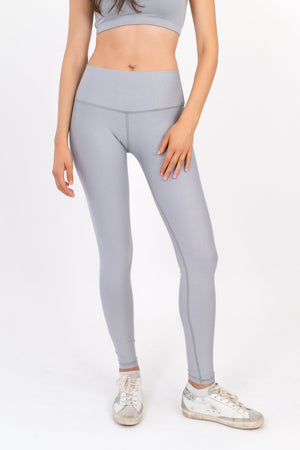 Light gray leggings close-up, contoured waistband and fitted legs.