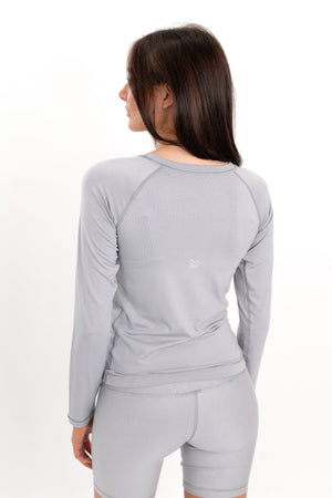 Gray long-sleeve crewneck shirt, back view with stitched seam lines and close fit.