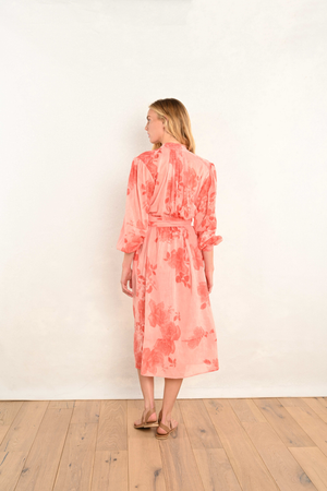 Coral pink floral midi dress, back view; long sleeves and tied waist detail.