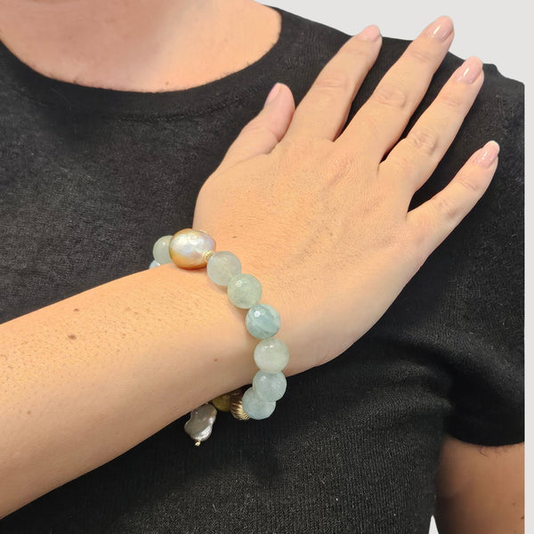 Light blue gemstone stretch bracelet on hand featuring pearl charm and faceted beads