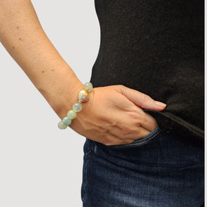 Light blue faceted gemstone stretch bracelet on wrist with pearl dangle charm