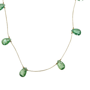 Closeup of light green faceted teardrop gemstone drops on thin necklace chain