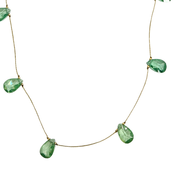 Closeup of light green faceted teardrop gemstone drops on thin necklace chain