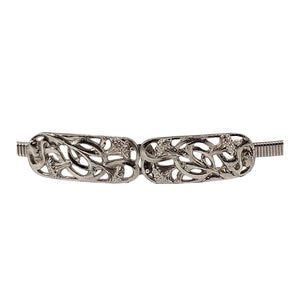 Silver stretch belt buckle with detailed scrollwork and textured side ends