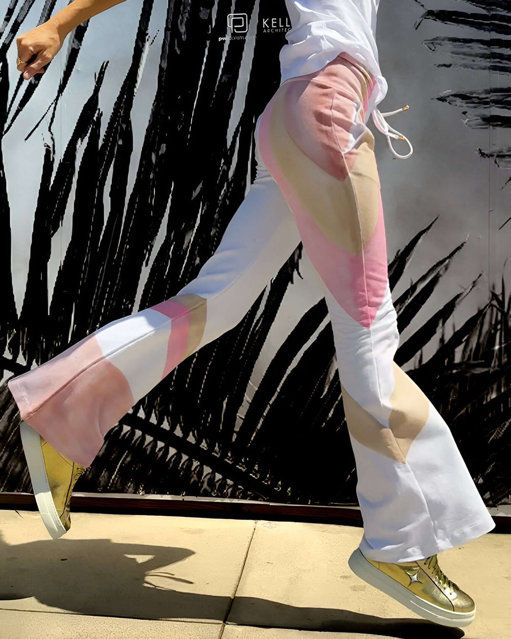 White flare sweatpants with drawstring and pink/beige geometric side panels.
