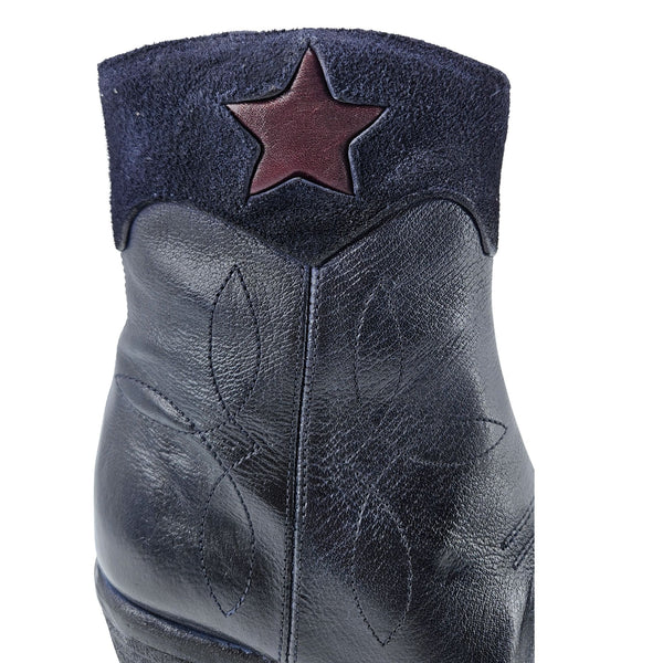 Navy leather ankle boot close-up with star patch on front shaft, textured finish