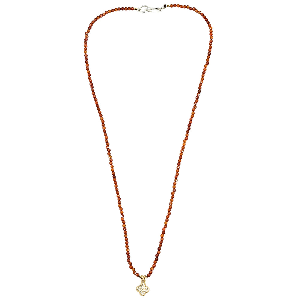 Orange beaded necklace with faceted beads and clover charm at center, silver clasp