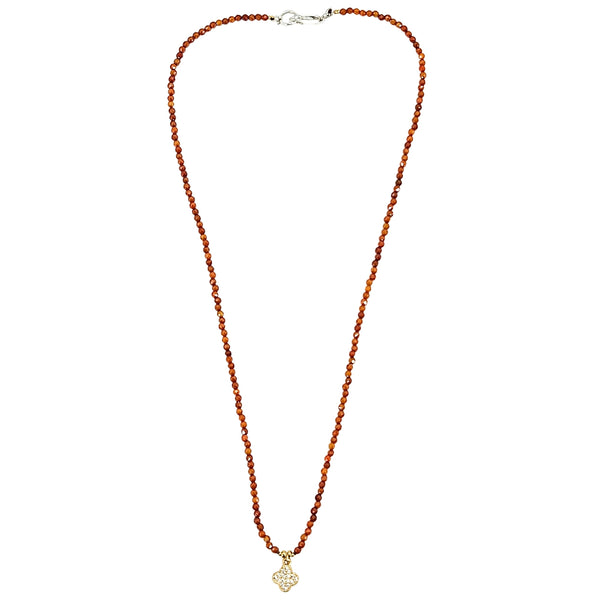 Orange beaded necklace with faceted beads and clover charm at center, silver clasp