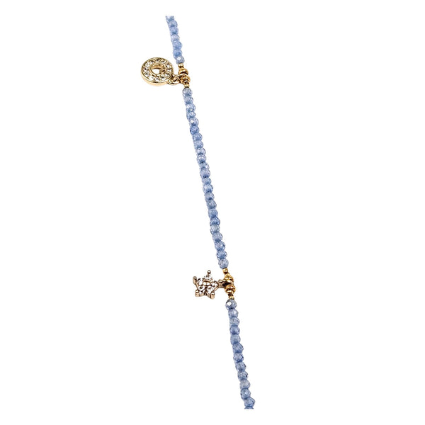 Charm necklace close-up: gold-toned heart charm and small star charms on blue beads