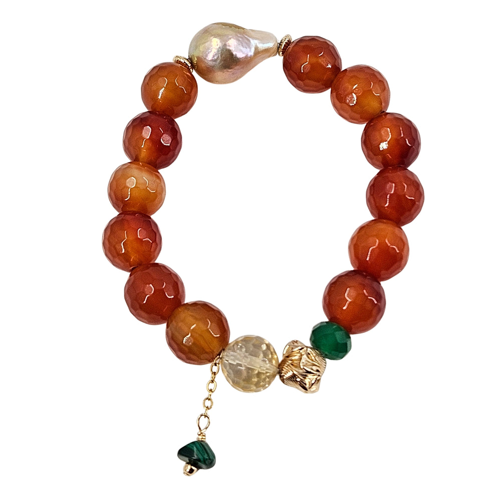 Stretch gemstone bracelet with red faceted beads, pale pearl spacer, and green dangle charm