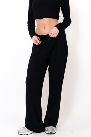 Black flow pants close-up, relaxed fit with drawstring tied at waist