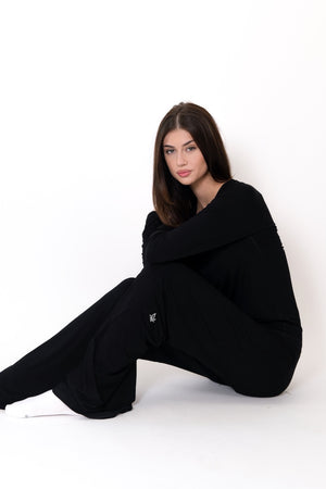 Black flow pants on model, seated pose showing drape and wide leg opening