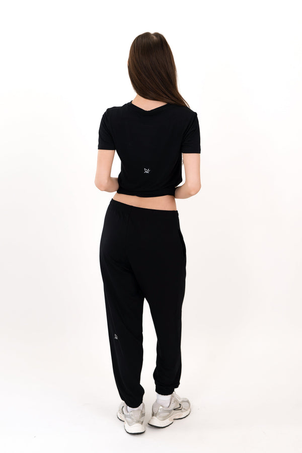 Black sweatpants, back view, relaxed legs with elastic ankle cuffs
