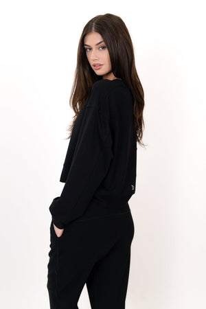 Black crew neck pullover with long sleeves, angled side view