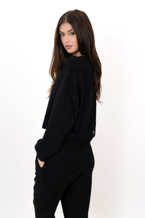 Black crew neck pullover with long sleeves, angled side view