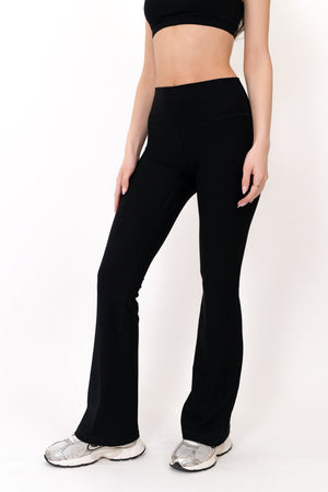 Black flare legging front close-up, fitted waist with wide bootcut opening at hem.