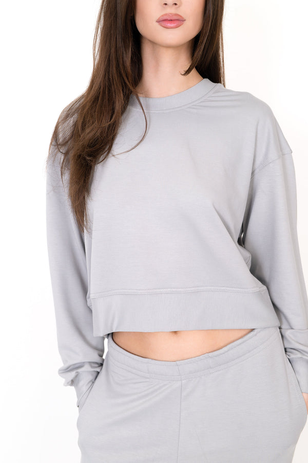Gray crew neck pullover with long sleeves and relaxed fit; cropped drawstring hem.