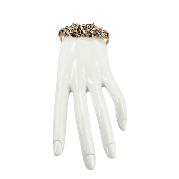 Gold rhinestone bracelet on display hand with arched band and crystal flower details