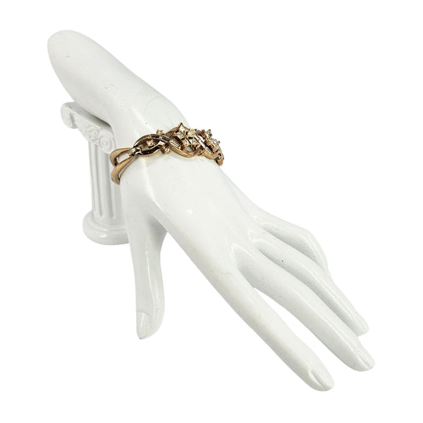 Gold rhinestone bracelet on hand, curved openwork links with crystal flower accents