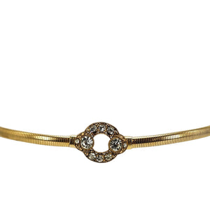 Gold tone stretch belt with ornate circle buckle centered with clear rhinestones