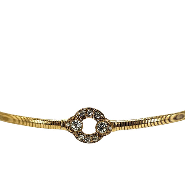 Gold tone stretch belt with ornate circle buckle centered with clear rhinestones
