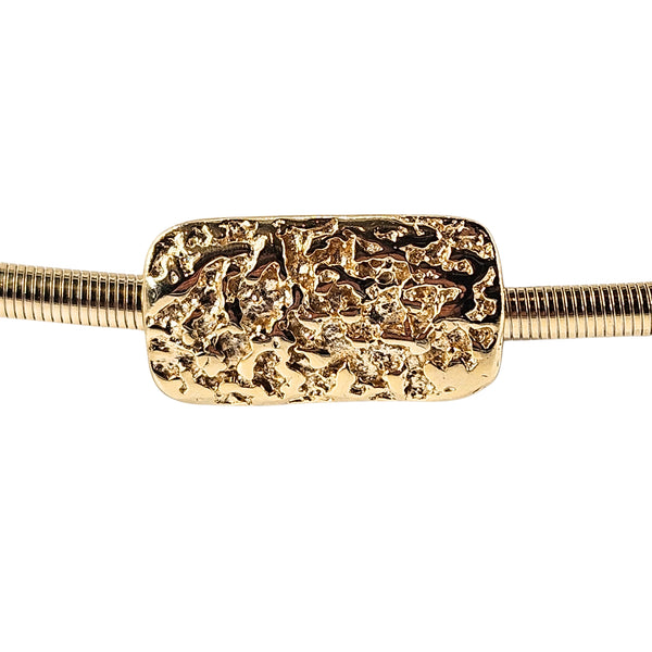 Gold stretch belt with ornate textured rectangular nugget buckle close-up
